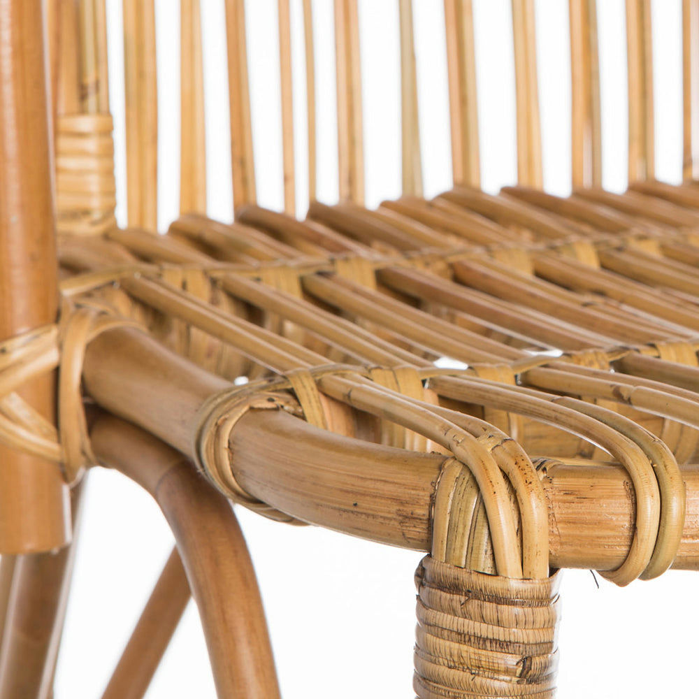 Un primer plano de la Silla de comedor en bambú y ratán Robert captura su diseño rústico, mostrando curvas naturales y uniones bien envueltas que encarnan la esencia del ratán tejido.