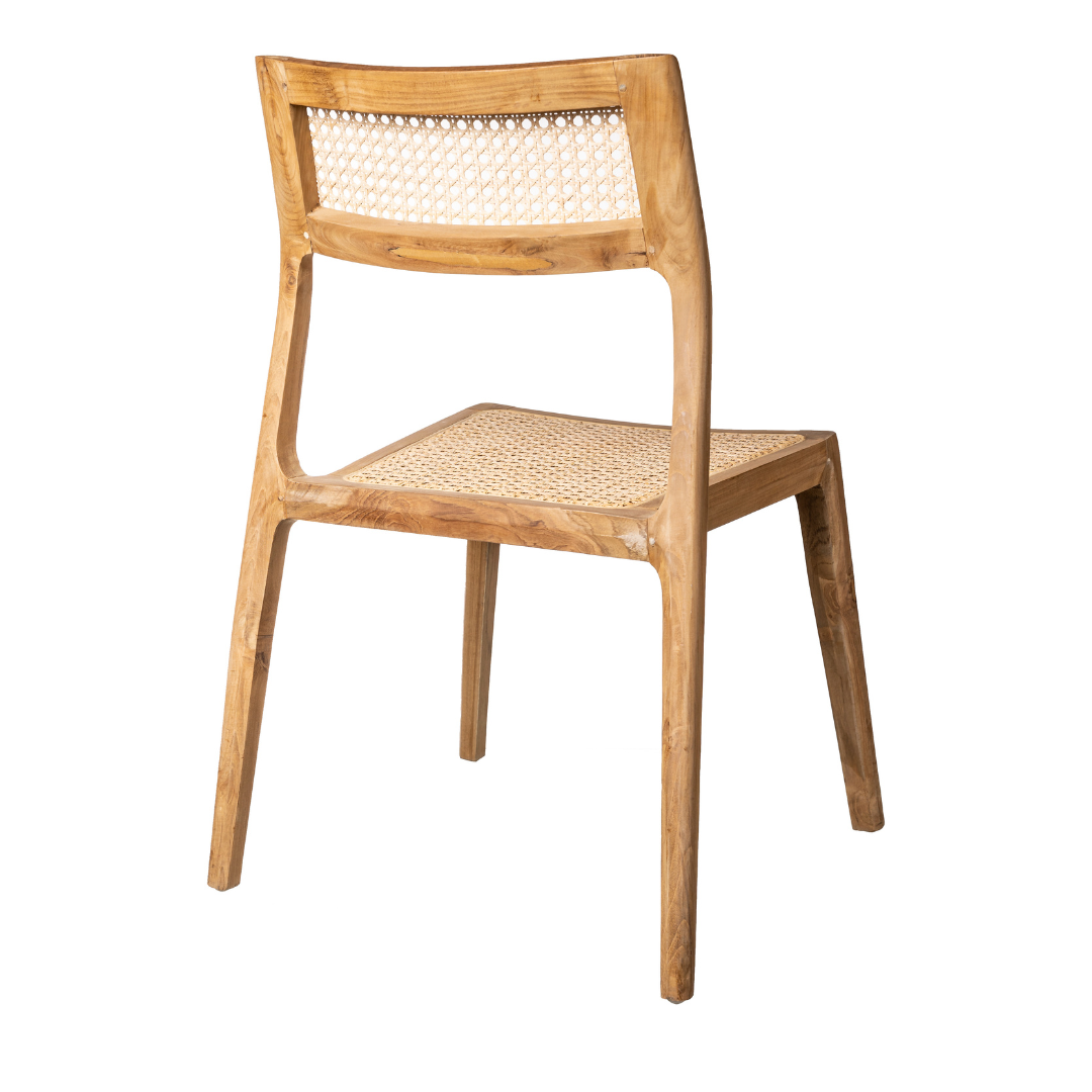 La Silla de comedor en madera de Teca Gabriela (Apilable) presenta un respaldo y asiento de caña tejida, visible desde un ángulo, resaltando su diseño ergonómico.