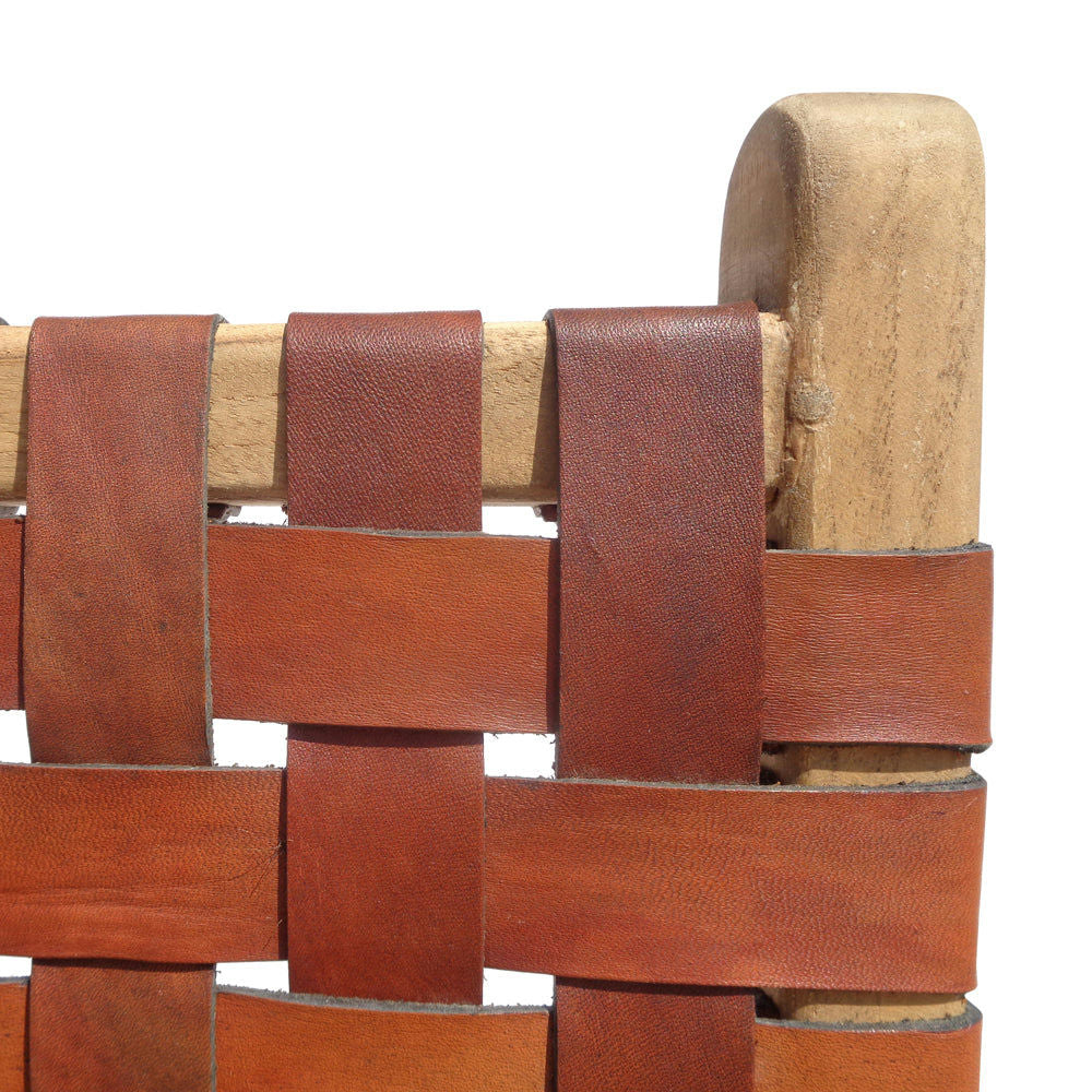 Primer plano de la Silla de comedor en madera de teca y cuero Zoe Brown, que presenta un asiento y respaldo de cuero marrón de tejido apretado sobre una robusta estructura de teca, resaltando el exquisito diseño artesanal.