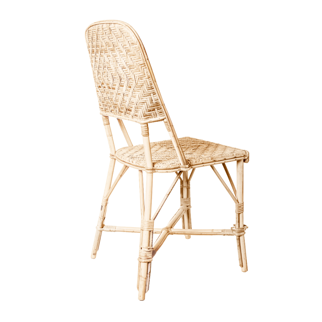La silla de comedor en ratán diseño natural Sara SB presenta un respaldo alto y patas curvas que encarnan un diseño minimalista. Vista de lado sobre un fondo blanco, destaca su elegancia natural.