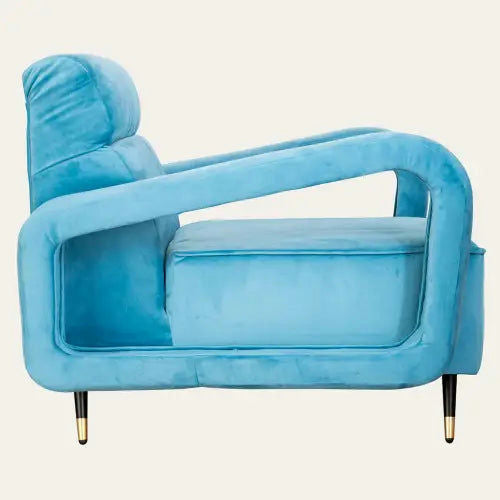 Vista lateral del sillón de terciopelo "Contemporánea" en azul moderno, con patas con puntas doradas, un cojín de felpa y un diseño moderno angular.