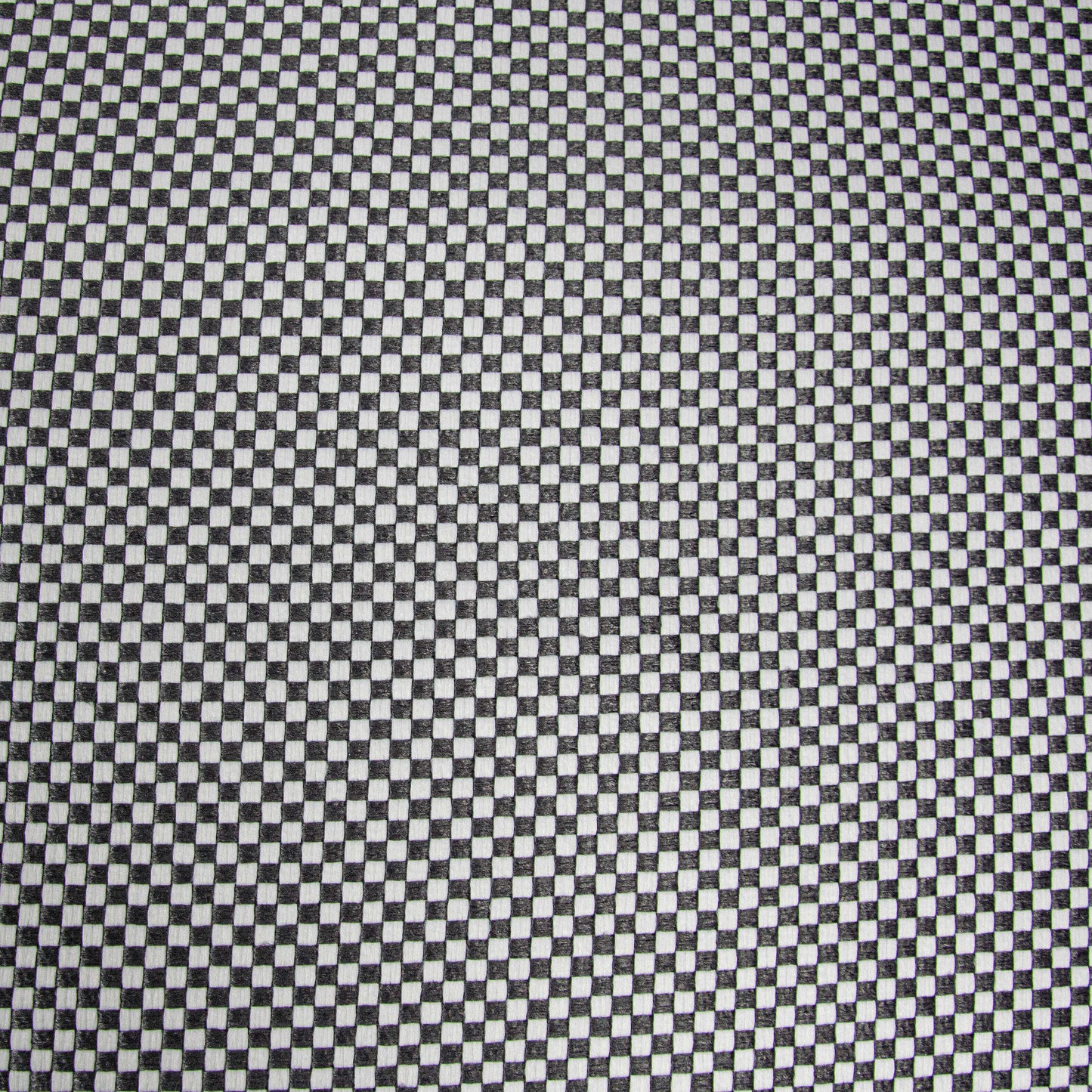 Un primer plano de un diseño en damero blanco y negro como el del puff cuadrado SOFTBOX CAPRI, fabricado con tejido OEKO-TEX repelente al agua y lavable para ofrecer estilo y comodidad en su salón, terraza o balcón (70×70×40 cm, compacto).