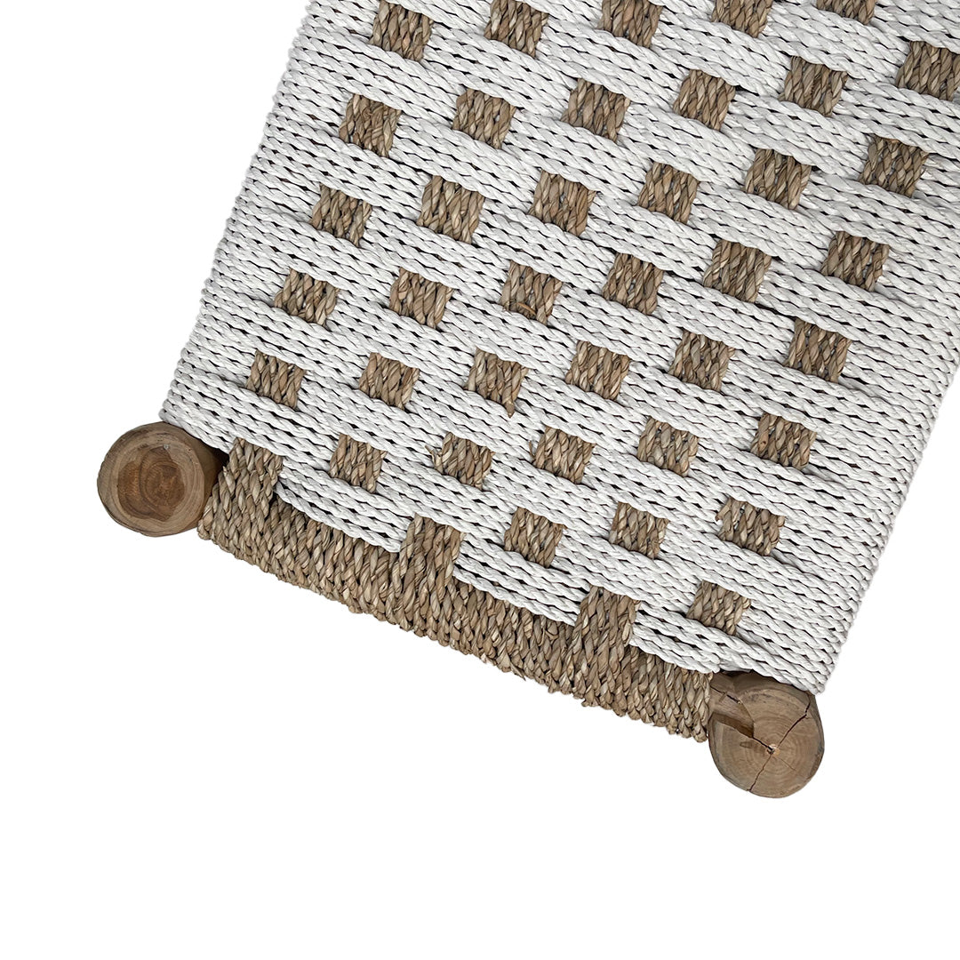 Primer plano de un tapete tejido con patrón de cuadros en blanco y tostado natural, anclado por esquinas de madera redondeadas, que recuerda al estilo Banqueta en Madera de Teca y Ratán Natwhit.
