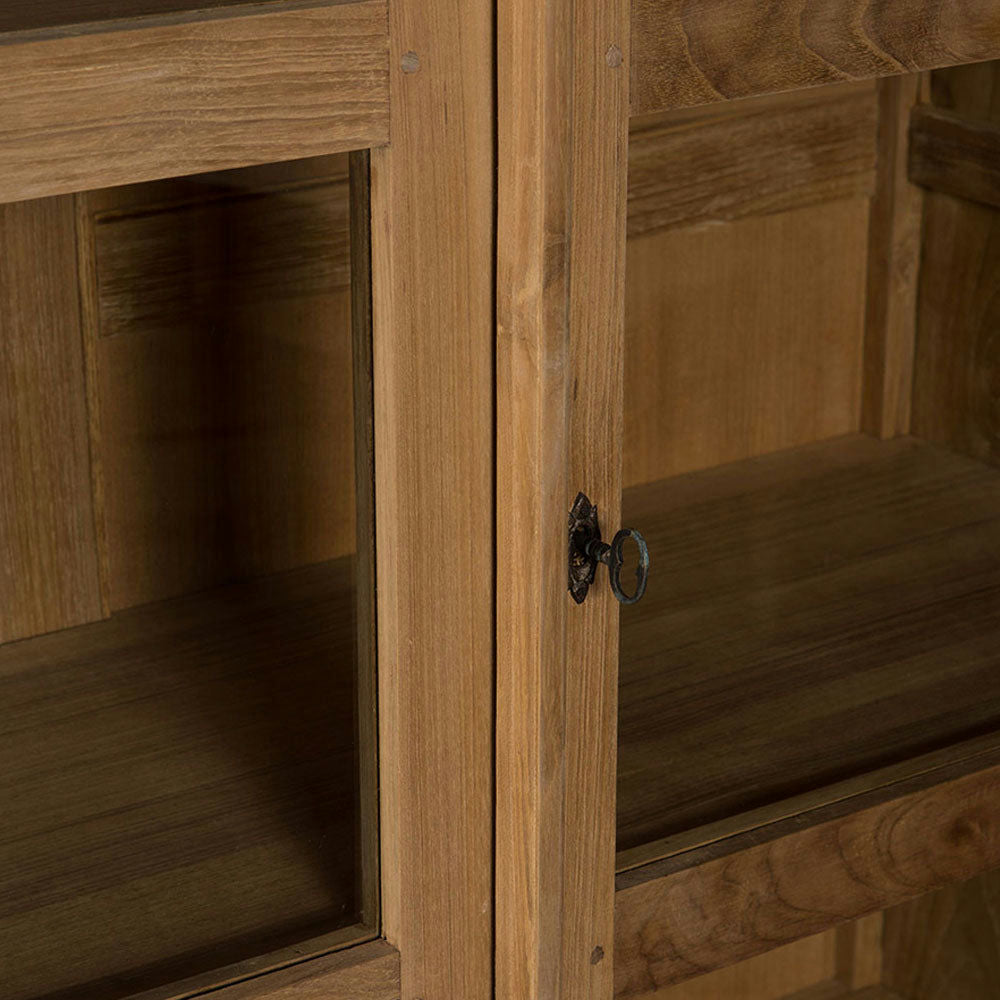 Primer plano de una Vitrina en Madera de Teca y Cristal Rico con puertas revestidas de vidrio, que presenta una llave decorativa de metal en la cerradura, que emana un aire de diseño contemporáneo.