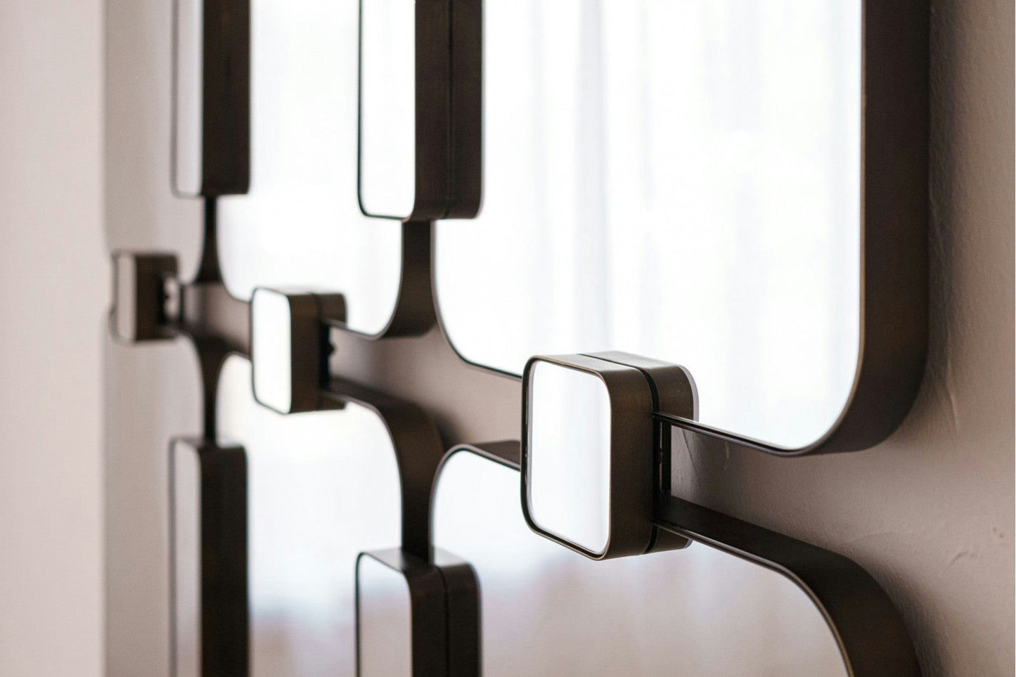 Primer plano del Espejo Rectangular Metal Industrial Evita, una moderna pieza de pared que presenta elementos metálicos cuadrados y rectangulares con superficies blancas dispuestos en un patrón geométrico.