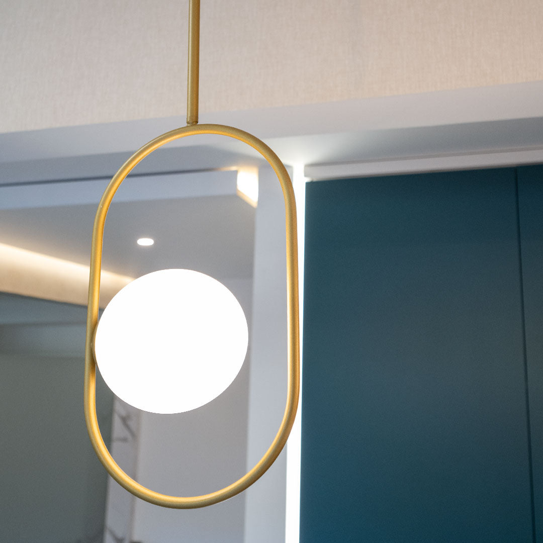 La Lámpara de Techo Colgante Moderna 3135-1C presenta un diseño colgante moderno con una bombilla circular blanca en un marco ovalado dorado, que incorpora diseño moderno e iluminación elegante, ideal para interiores minimalistas.