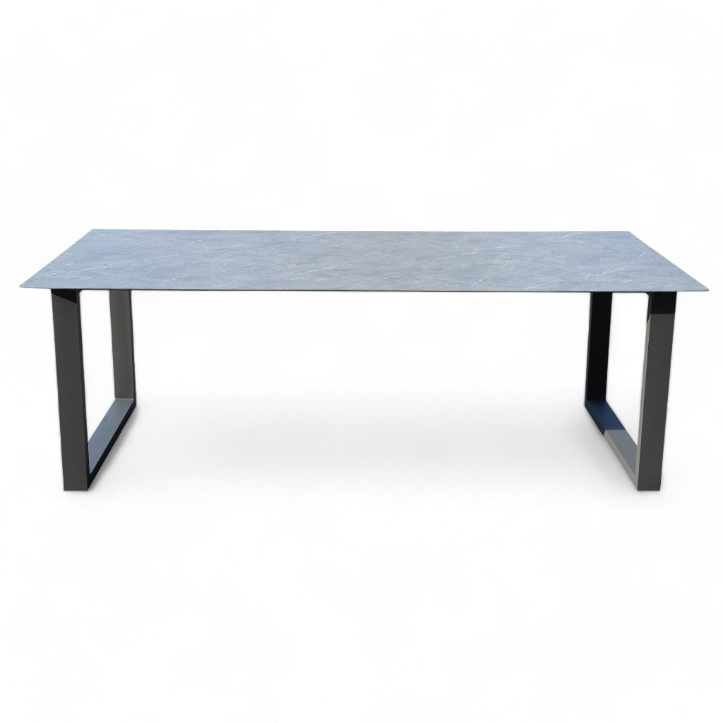 Mesa de comedor de exterior SILK en aluminio antracita y cristal cerámico (220 × 100 × 75 cm), estilo moderno, ideal para jardín o terraza. Fotografía sobre fondo blanco mostrando su superficie lisa y patas negras.