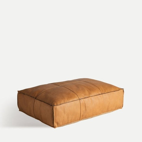 El Puff rectangular de piel marrón con costuras Boussac B se asienta elegantemente sobre un fondo blanco liso.