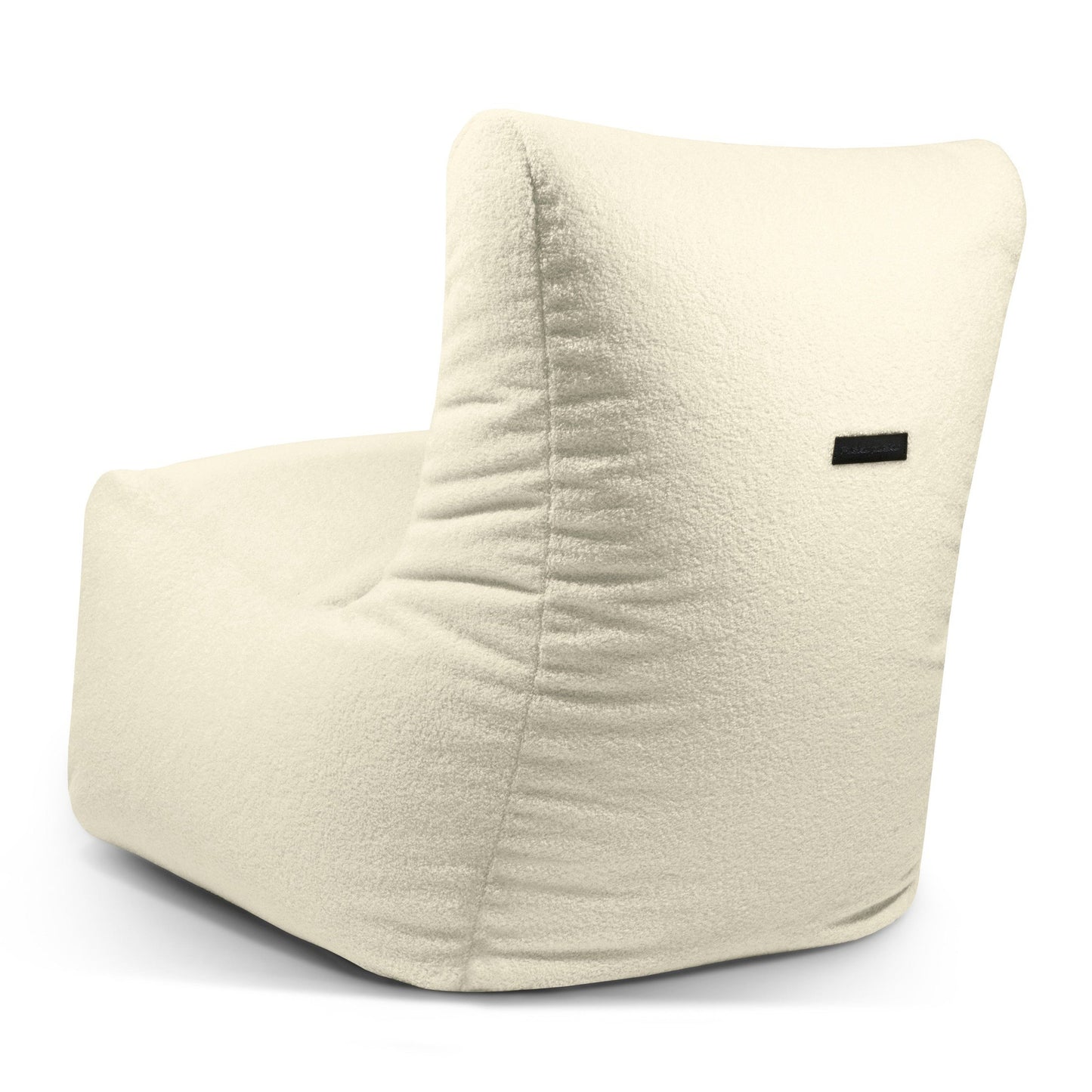 El Bean bag Seat Teddy es un moderno sillón sin brazos de color crema con tejido de felpa texturizado y una pequeña etiqueta negra, diseñado como un asiento ergonómico que recuerda a un elegante sillón estilo puff.