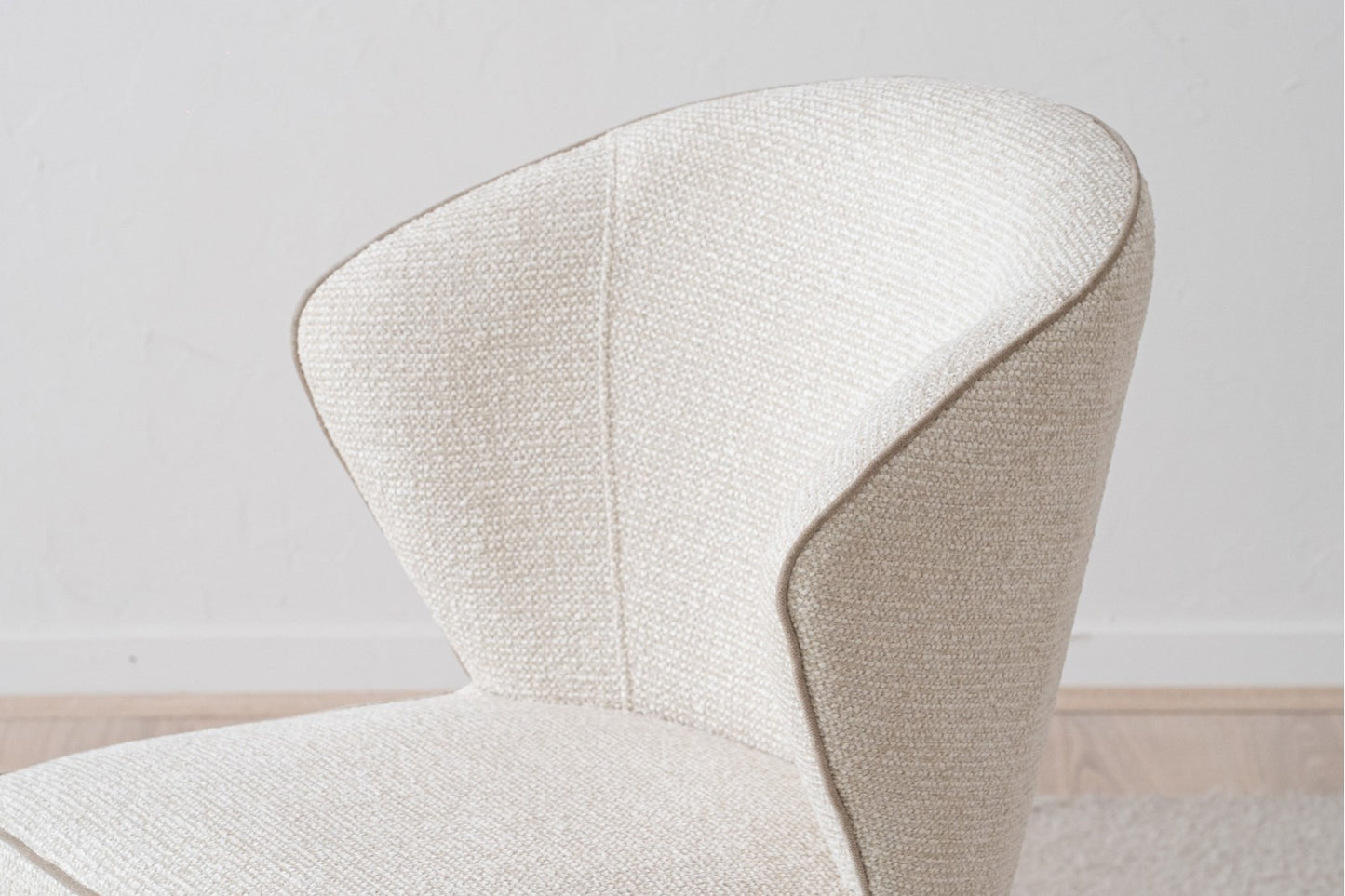 Pack 2 Sillas de comedor tapizadas EVA en tejido texturizado de color crema con respaldo curvo y diseño contemporáneo minimalista sobre pared gris claro y suelo de madera.