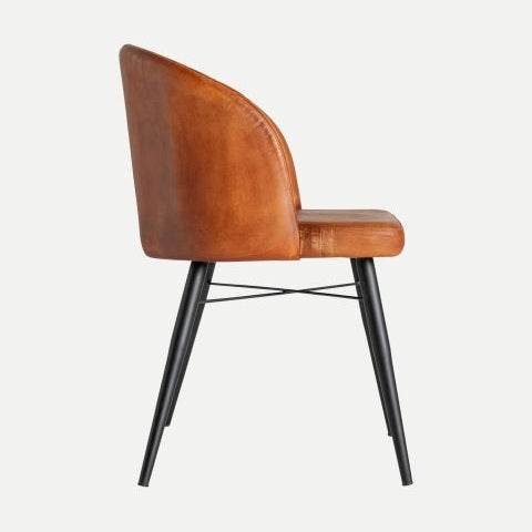 La Silla de comedor en piel y metal Luard ofrece estilo y funcionalidad, con un acabado de cuero marrón, respaldo curvo y elegantes patas de metal negro. Su diseño moderno destaca sobre un fondo liso, mostrando elegancia en la vista lateral.
