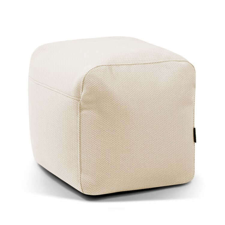 El Pouf Plus 50 Canaria es una otomana cúbica de color beige con un sutil dibujo de espiga, diseñada para su uso en exteriores. Versátil y elegante, complementa cualquier espacio. Se muestra sobre fondo blanco.