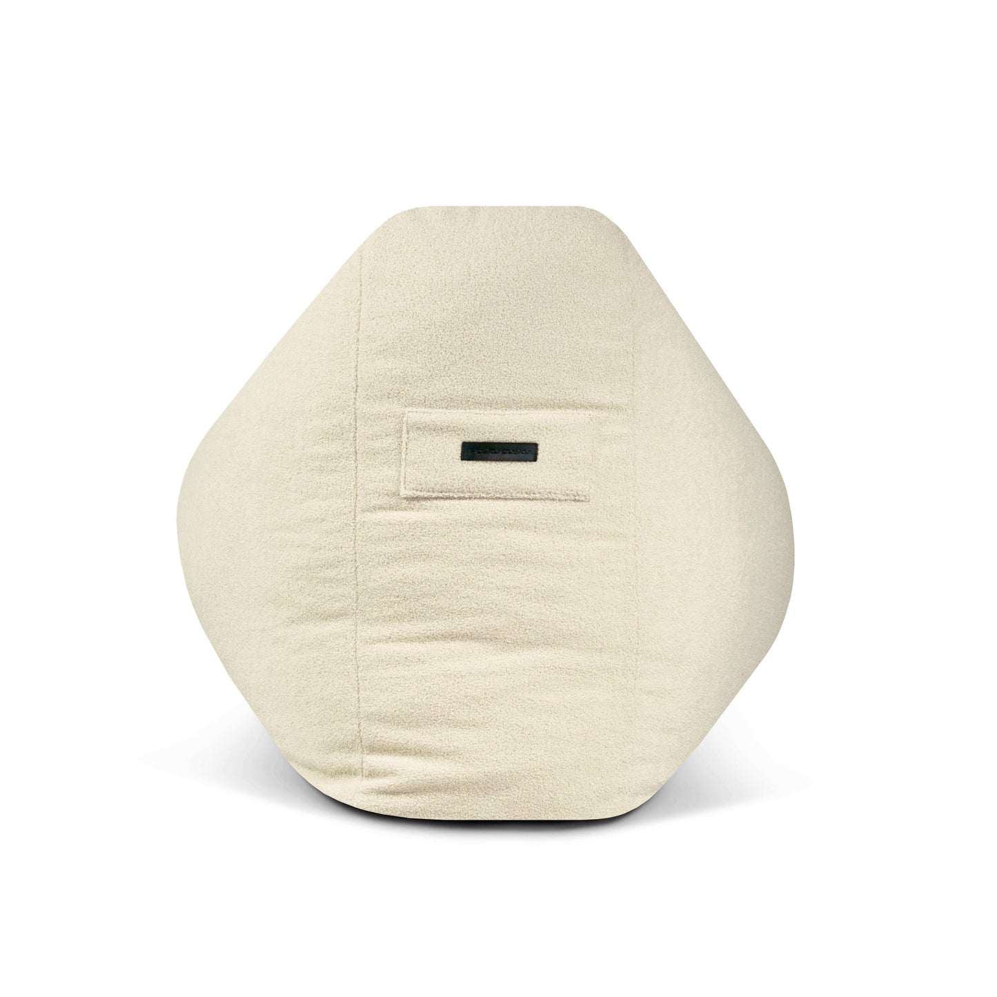 El Puff grande de espuma y borreguito 110×100×74 cm SNUG 100 TEDDY es un cojín hexagonal de color crema con una pequeña etiqueta negra en la parte delantera central, ideal para añadir comodidad y estilo moderno a su salón o dormitorio.