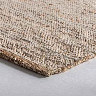 Una alfombra con borlas sobre un suelo de madera.