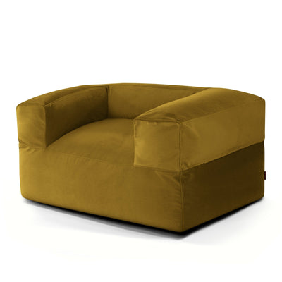 Un sillón cuadrado de terciopelo de color amarillo mostaza, con brazos bajos y anchos y un diseño moderno y cuadrado sobre un fondo blanco.