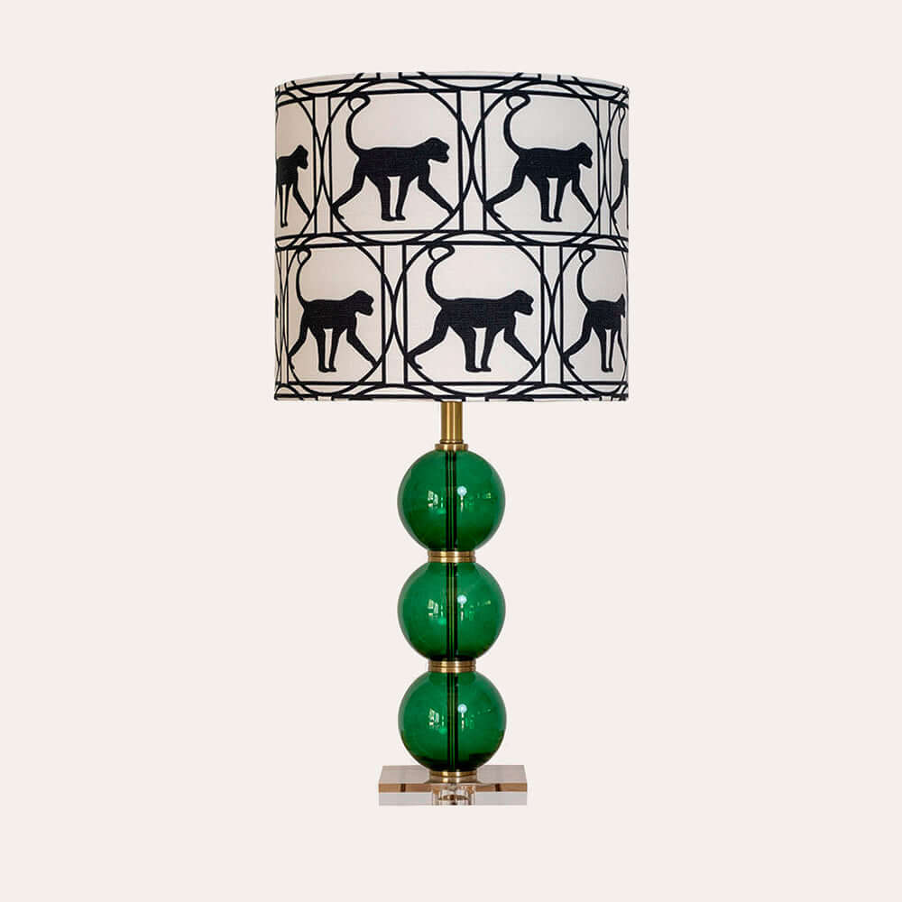 Una lámpara con pantalla verde y un gato negro encima.