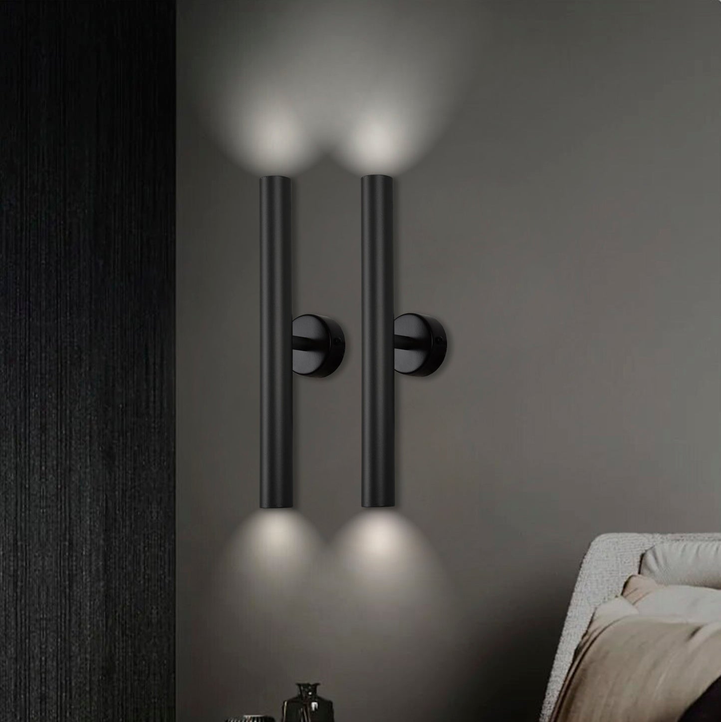 Dos apliques de pared verticales negros, Aplique de pared en acero con 2 puntos de luz Caia simple, iluminan hacia arriba y hacia abajo junto a una cama contra una pared de textura oscura, incorporando un diseño industrial moderno.