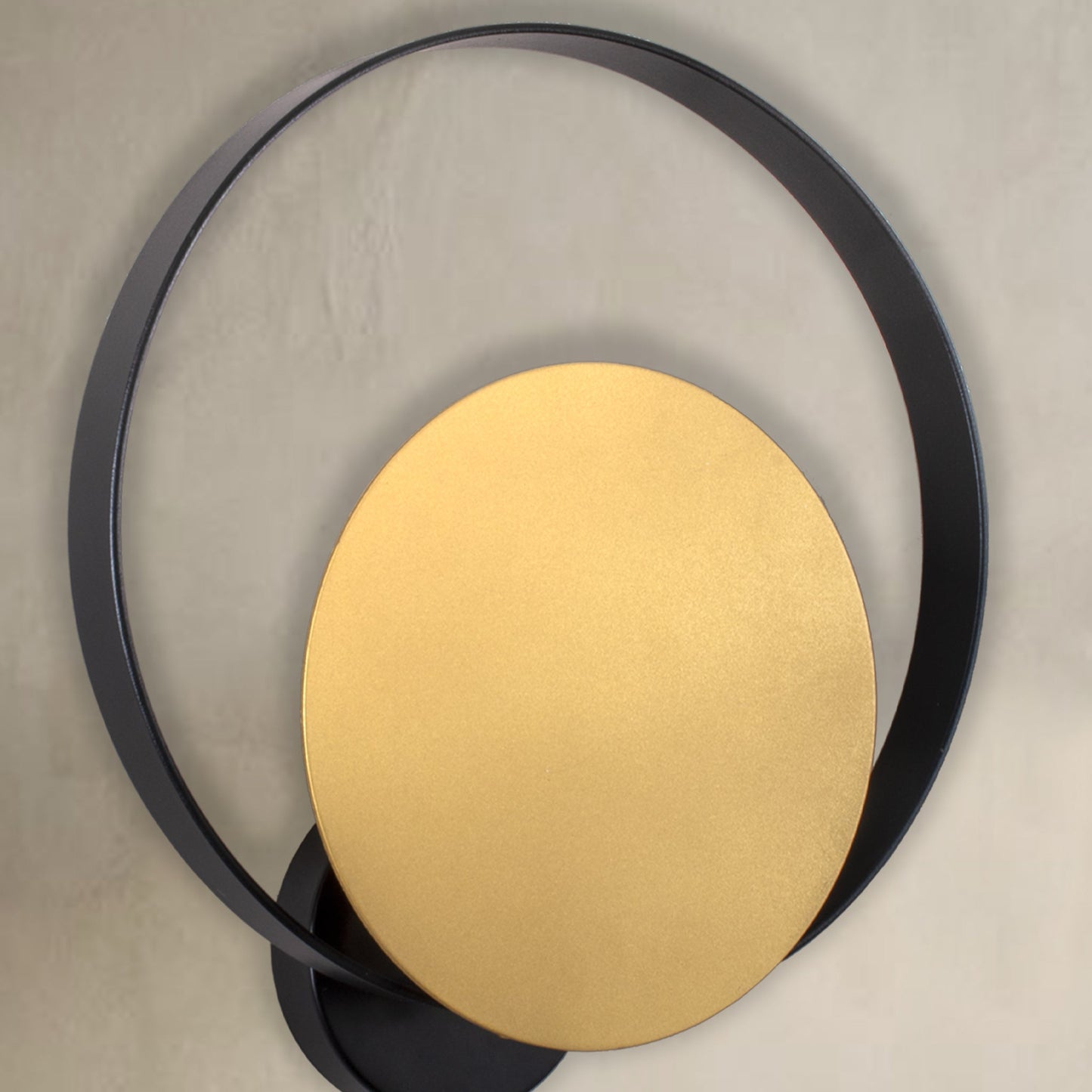 La luminaria de pared Echo II, con su marco circular negro y su disco central dorado sobre un fondo neutro, encarna el diseño contemporáneo para ofrecer una iluminación suave.