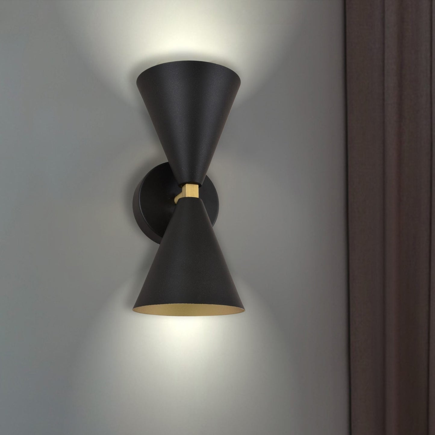 El aplique de pared de acero con 2 puntos de luz Nyx presenta un elegante diseño de doble cono negro, instalado elegantemente en una pared texturizada cerca de una cortina oscura, agregando un toque de estilo contemporáneo.