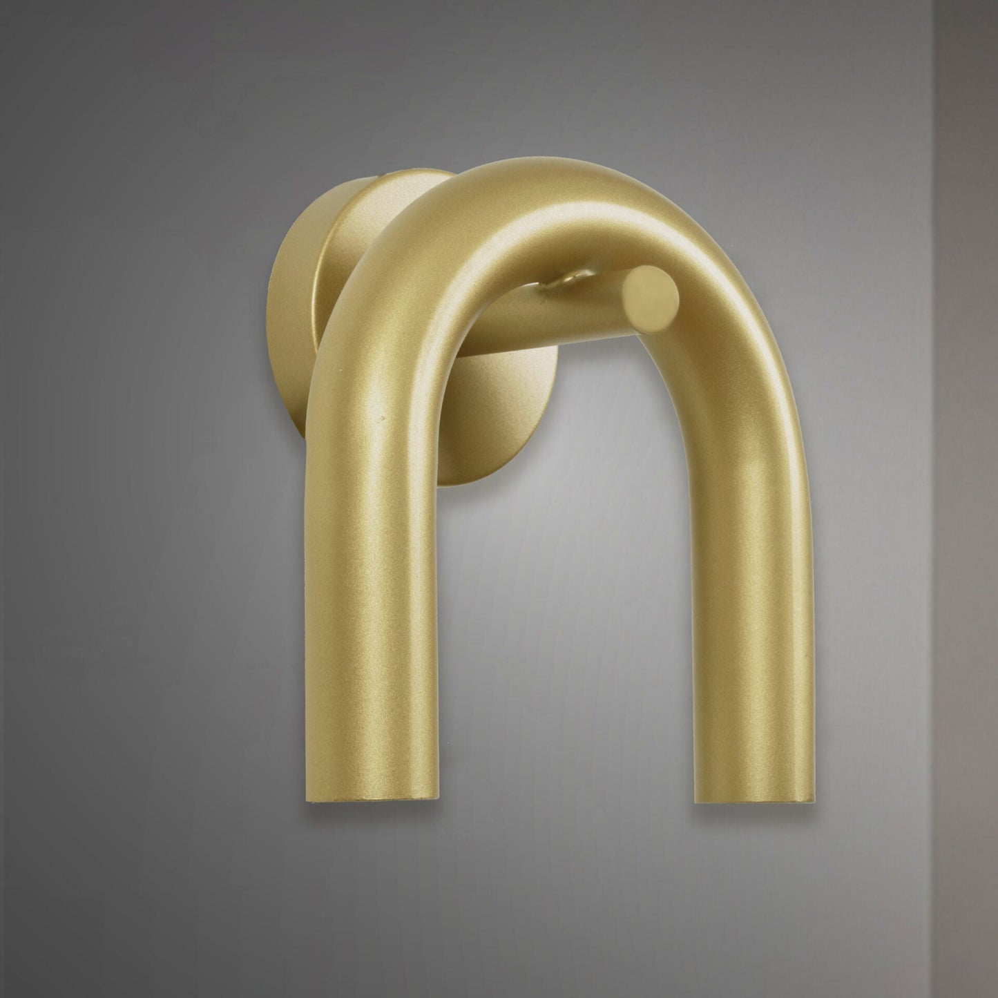 El Aplique de pared en acero con 2 puntos de luz Rhea presenta un acabado metálico dorado y un diseño en forma de U, que encarna un estilo de diseño contemporáneo sobre un fondo gris.
