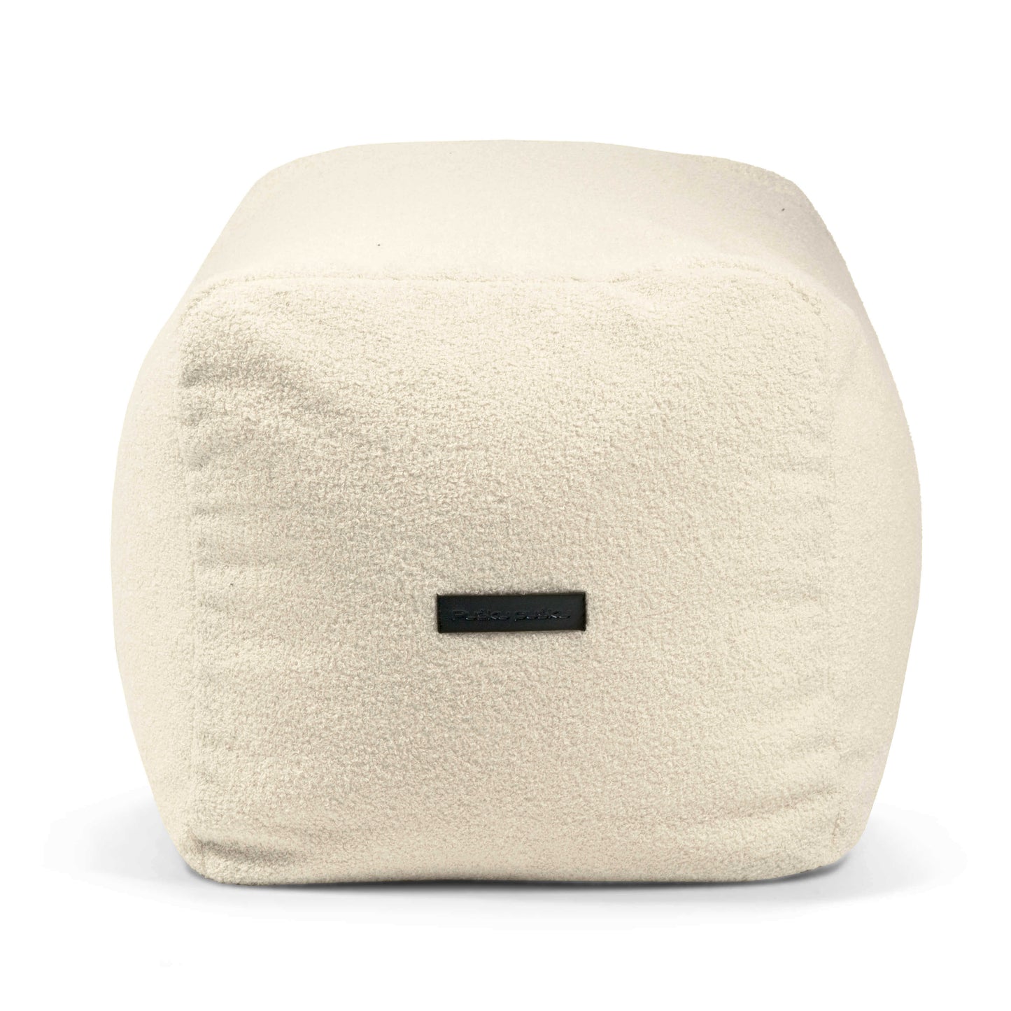 El Pouf rectangular de tela borreguito PLUS 70 TEDDY (70×60×45 cm) es compacto, ligero y moderno, con tela suave y una pequeña etiqueta negra, ideal para dormitorio o salón; proporciona comodidad y soporte ergonómico.