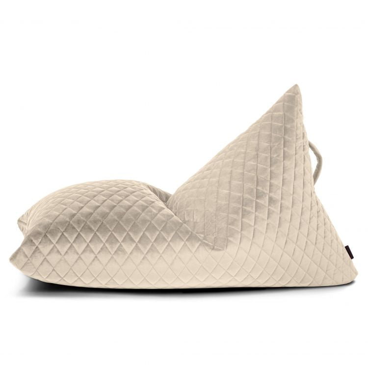 El puff infantil de terciopelo acolchado RAZZY LURE LUXE (75×110×65 cm) presenta un acabado de terciopelo beige acolchado y un respaldo triangular, mostrado de lado sobre fondo blanco.