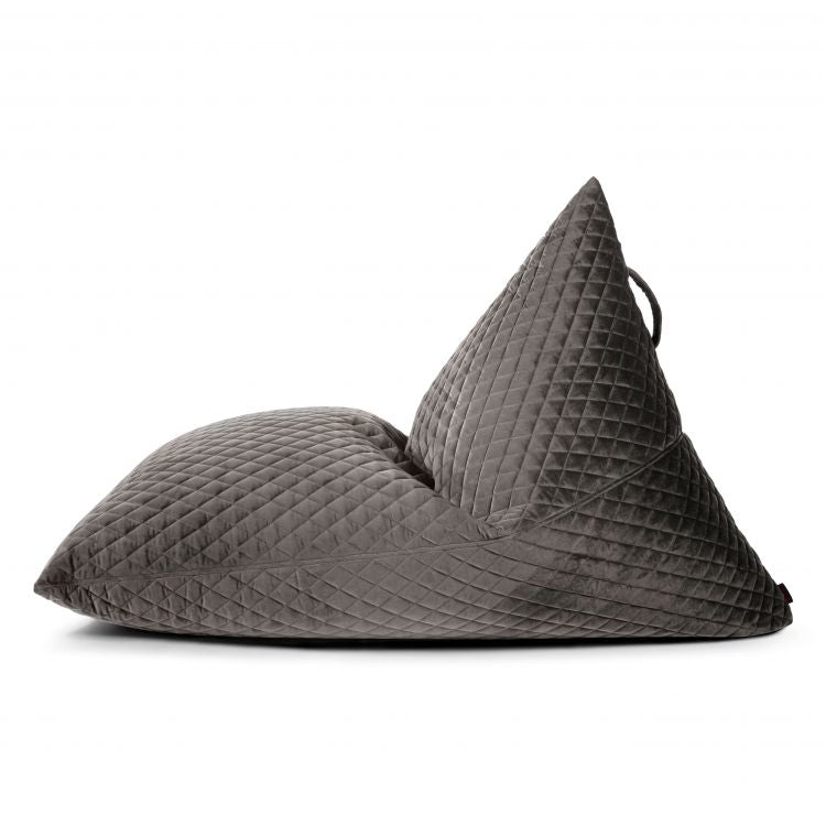 Un gran sillón de terciopelo acolchado (RAZZMATAZZ LURE LUXE, 155×120×95 cm) en gris oscuro con respaldo triangular, mostrado de perfil sobre fondo blanco, ideal para salones modernos, dormitorios o espacios chill-out.