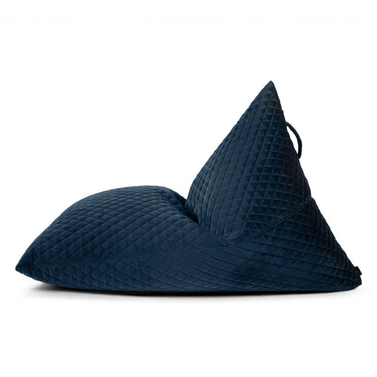 Un gran puf acolchado de terciopelo azul oscuro (155×120×95 cm), RAZZMATAZZ LURE LUXE, de lado sobre fondo blanco, de estilo moderno para el salón, el dormitorio o los espacios chill-out.