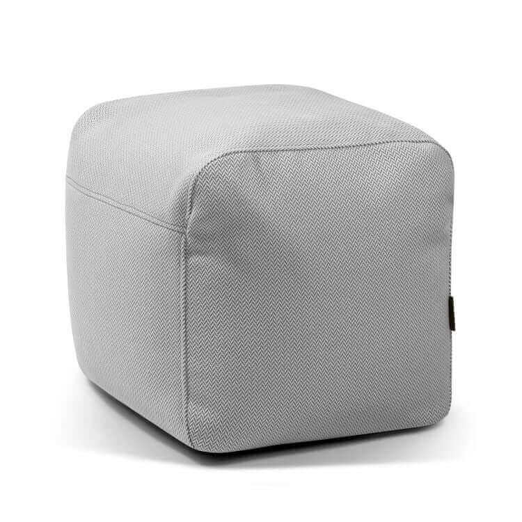 El Pouf Plus 50 Canaria es un puf cuadrado de color gris claro con sutil textura de espiga sobre blanco, perfecto como asiento versátil para cualquier espacio y apto para exteriores.