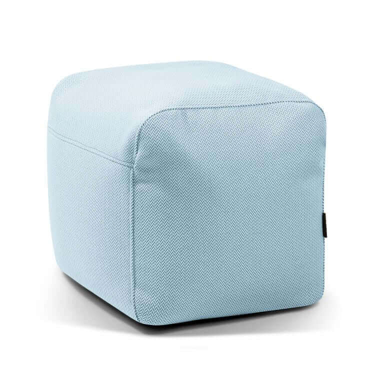 El Pouf Plus 50 Canaria es un puf cuadrado de color azul claro con un diseño de espiga y una pequeña etiqueta negra, que se muestra sobre un fondo blanco. Ideal como asiento versátil para cualquier espacio, y apto para uso exterior.