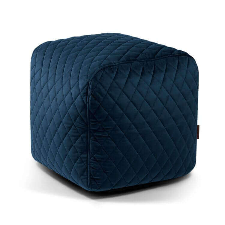 El PLUS 50 LURE LUXE es un puf cuadrado de terciopelo acolchado azul oscuro (50×50×35 cm), compacto y ligero, de tejido suave y bordes redondeados, ideal para dormitorios o salones modernos. Sobre un fondo blanco liso.