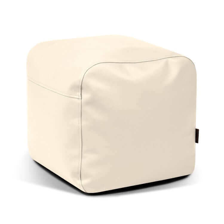 El Pouf Plus 50 Outside - uso exterior es un puf en forma de cubo de color crema con exterior liso y costuras visibles que ofrece un asiento cómodo, lo que lo convierte en un mobiliario versátil sobre un fondo blanco.