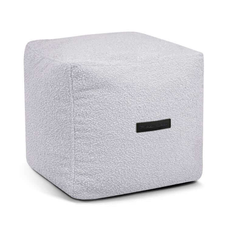 El Puff cuadrado de tela bouclé 45×45×40 cm de UP MADU, en gris claro con tejido extra suave y una pequeña etiqueta negra en un lado, se muestra sobre un fondo blanco, ideal para dormitorio o salón.