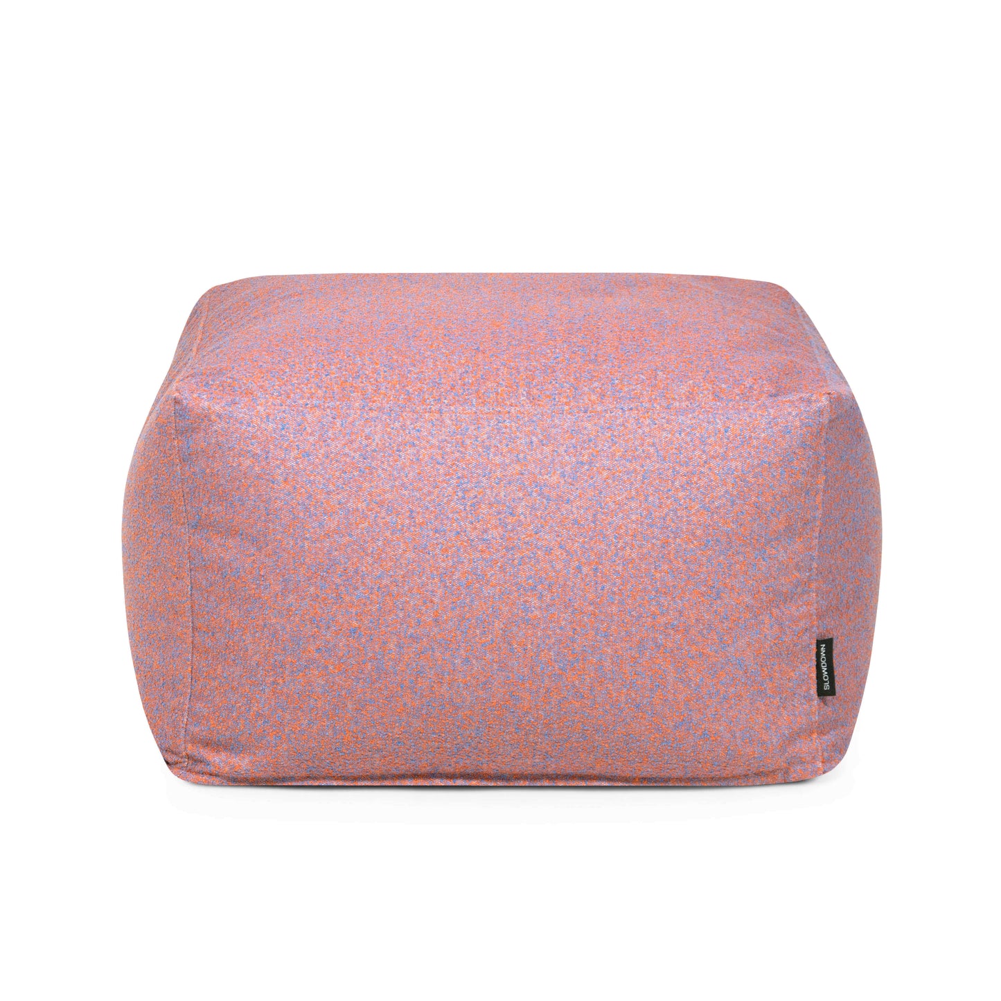 Un puf rectangular Softbox Breeze - uso exterior con motas moradas y naranjas, una etiqueta de marca negra visible en la parte inferior derecha, sobre fondo blanco.