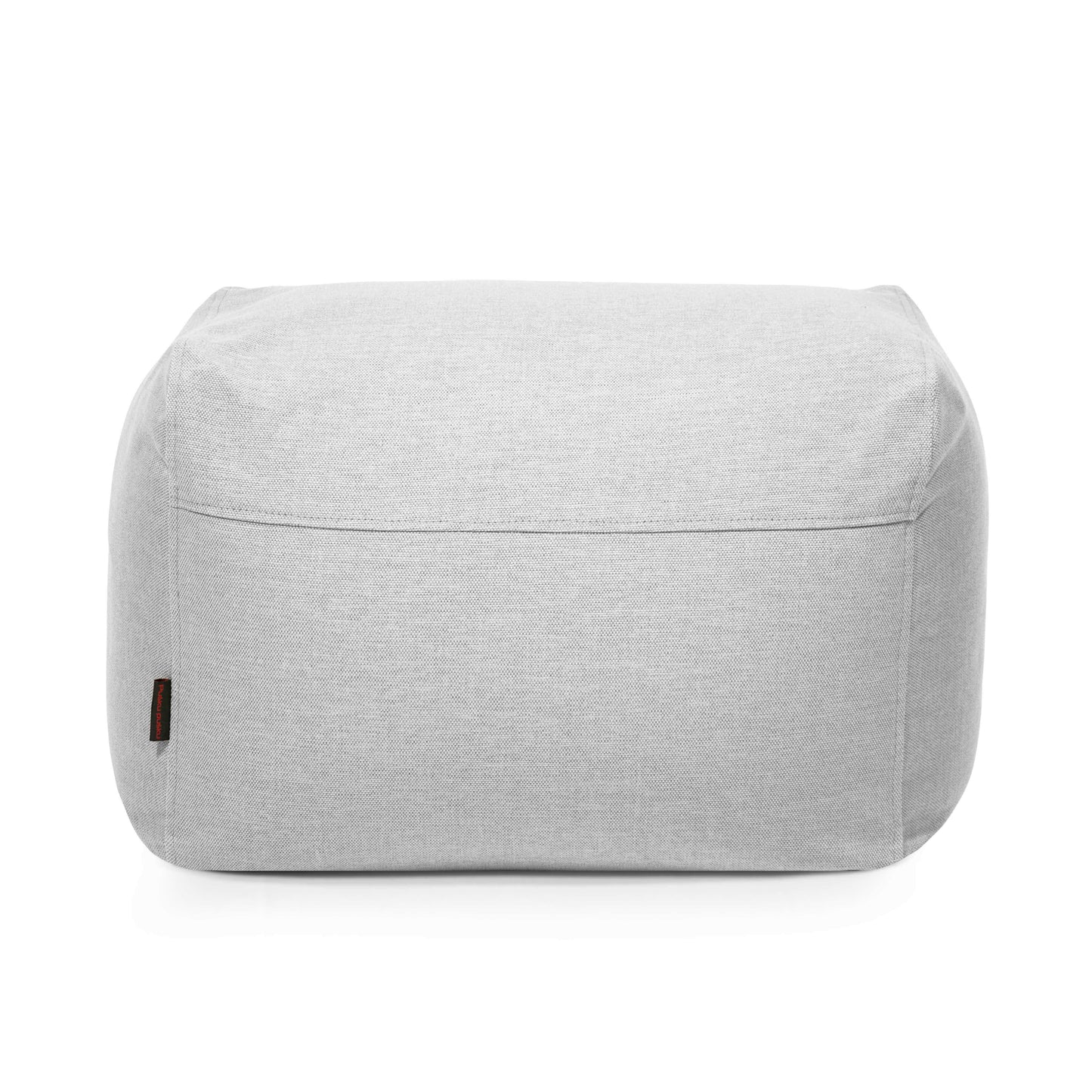 El Pouf Plus 70 Casa - uso exterior es un puf rectangular de tela gris claro con costuras visibles y una pequeña etiqueta en el lado izquierdo, perfecto como puf de exterior o asiento de jardín, mostrado sobre fondo blanco.