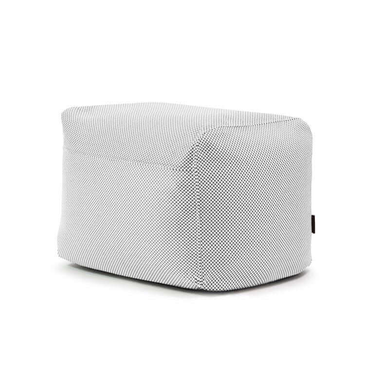 Puf Plus 70 Capri rectangular de tela gris con bordes redondeados, tejido OEKO-TEX, textura sutil y una pequeña etiqueta lateral negra. Ideal como reposapiés ergonómico o puf elegante para uso en interiores y exteriores.