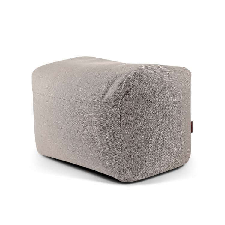 La PLUS 70 NORDIC es una otomana rectangular de tela suave y lavable de color gris claro (70×60×45 cm), compacta y ligera, ideal para el dormitorio o el salón, que se muestra con bordes redondeados sobre fondo blanco.