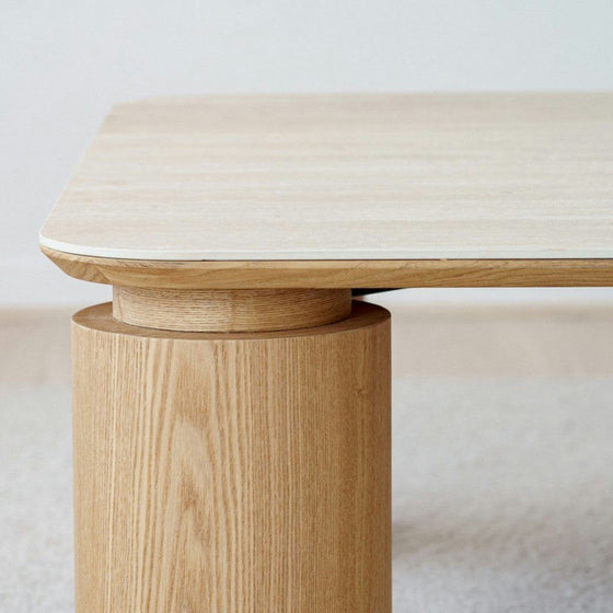 Primer plano de una Mesa de centro cuadrada en cerámico DM y fresno natural Línea, con líneas limpias y vetas de madera natural, perfecta para un salón contemporáneo.