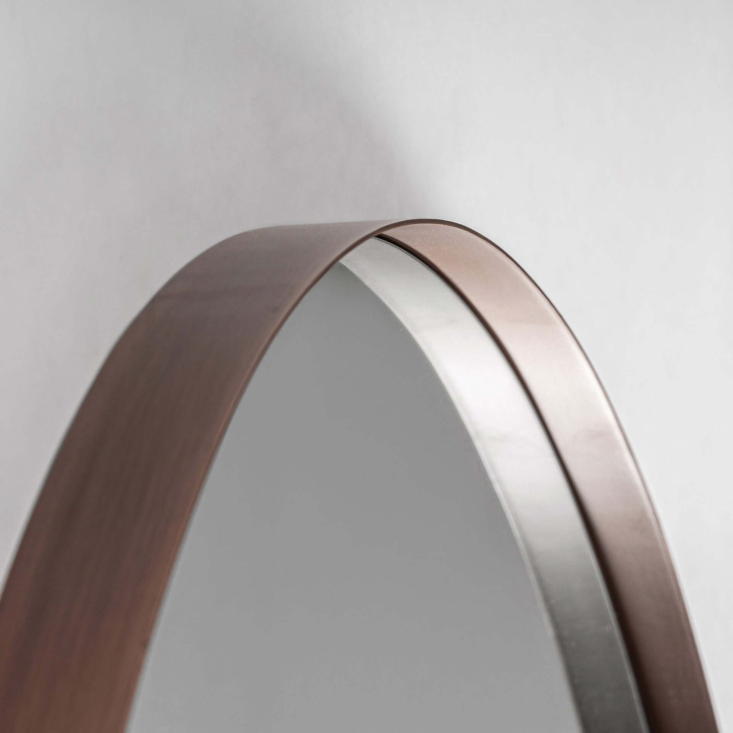 Detalle del borde superior del Espejo de pared grande en hierro bronce 120×5×180 cm - moderno - VULC, con marco de hierro marrón sobre fondo liso gris claro.
