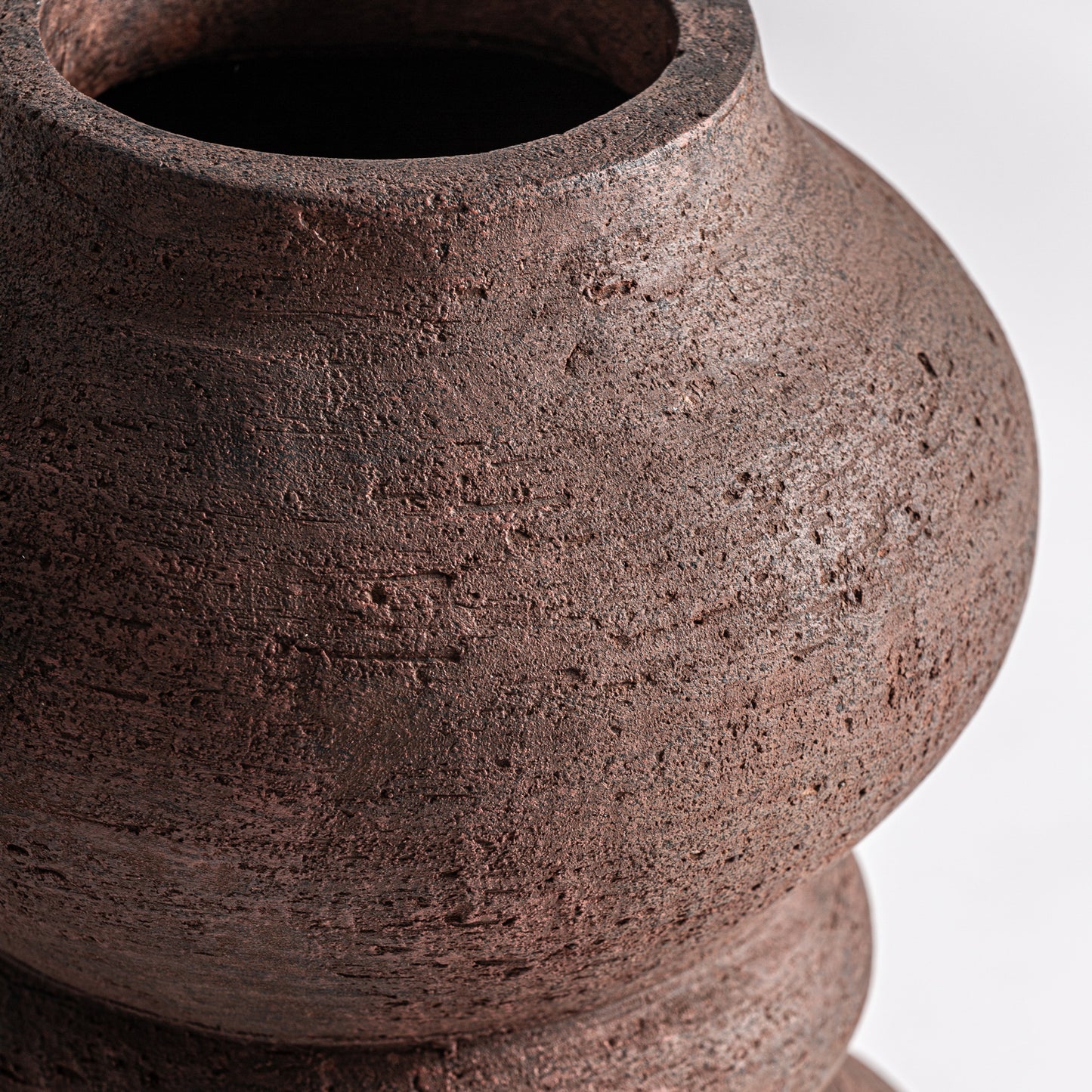 Detalle del Jarrón en terracota mate 21×21×36 cm - contemporáneo - OKAR L, con superficie marrón texturizada, cuerpo redondo ancho y abertura estrecha -ideal para la decoración del hogar- sobre un fondo blanco liso.