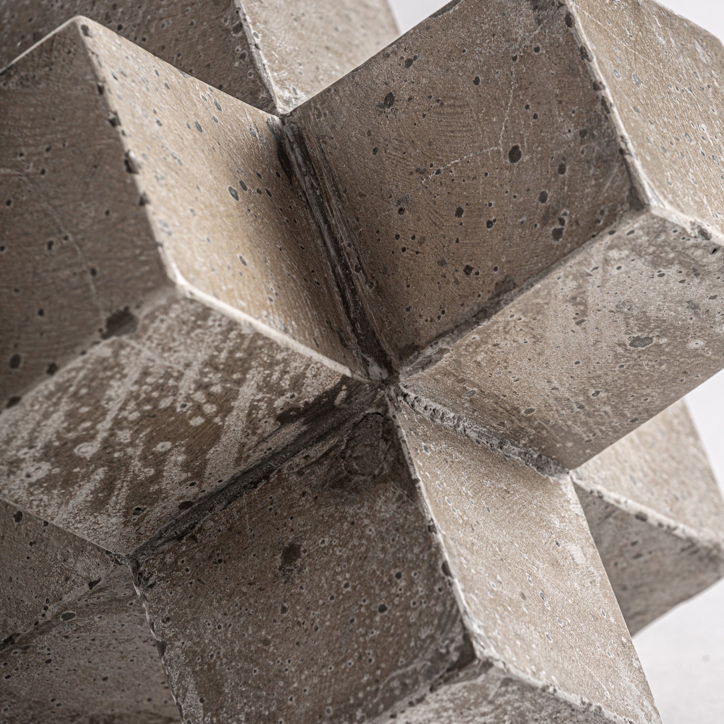 Detalle de la figura decorativa KUBO en cemento beige tallado y arena (22×22×22 cm), con cubos geométricos entrelazados y acabado texturizado, perfecta para añadir un toque contemporáneo a cualquier espacio.