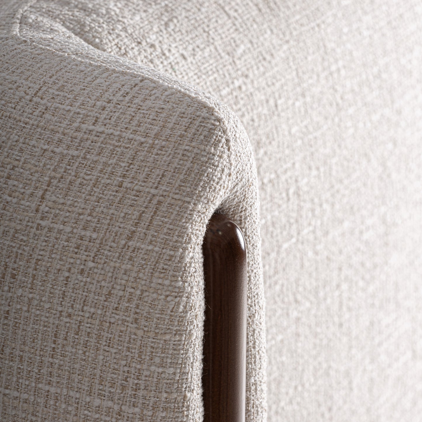 Primer plano de un sofá de tela con textura beige y detalle de marco de madera visible, ideal para combinar con el Cabecero tapizado blanco roto y madera de fresno marrón 215×22×114 cm - contemporáneo - VILDE en un dormitorio moderno.