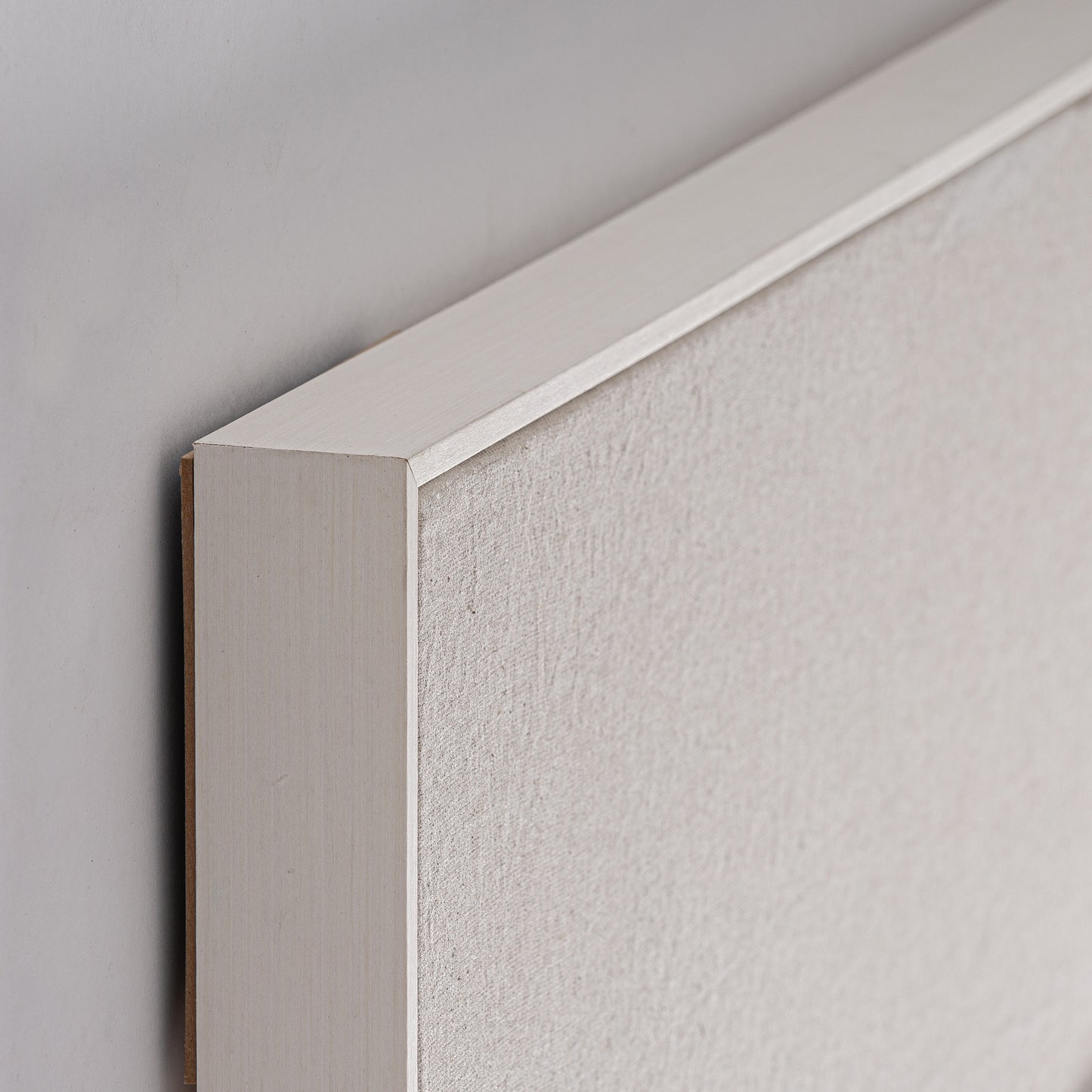 Primer plano del cuadro geométrico ZILIA, con lienzo blanco roto de 120×5×160 cm y marco de madera de pino marrón montado en una pared clara, que muestra la textura del lienzo y los detalles de las esquinas en un estilo contemporáneo.