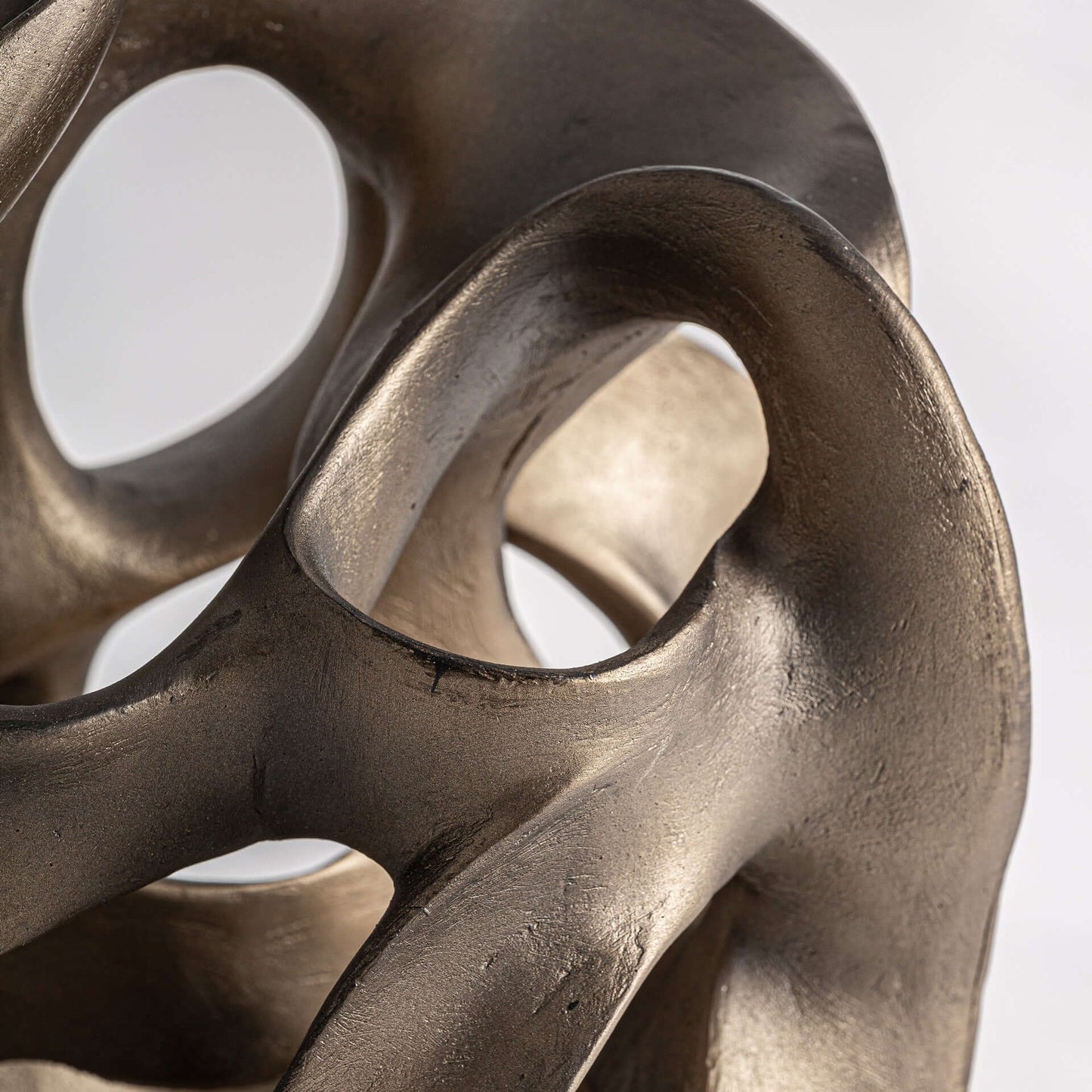 Primer plano de la Figura decorativa en resina oro viejo 23×26×40 cm - contemporáneo - URANIA, esta pieza escultórica presenta superficies lisas y curvas y aberturas ovaladas que evocan elegancia y modernidad.