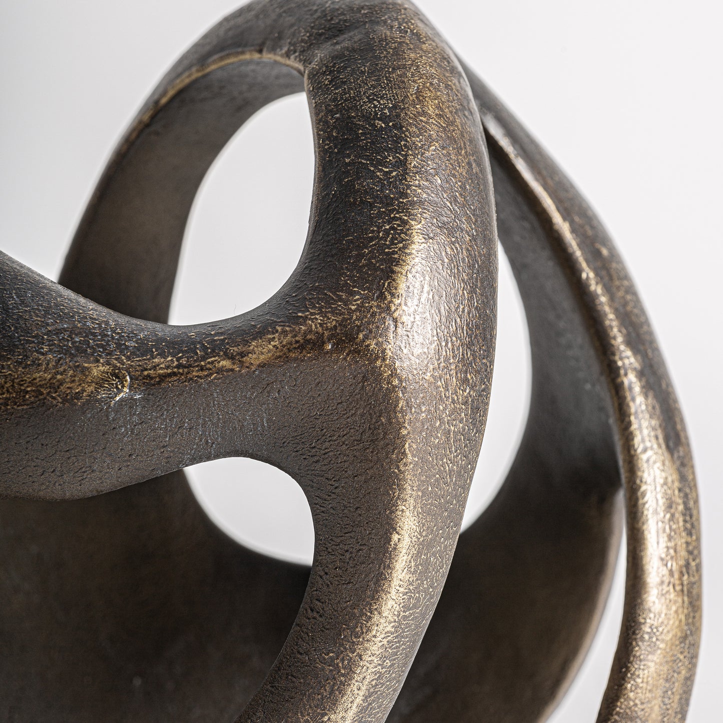 Detalle de la Figura decorativa en resina oro viejo 22×23×34 cm - contemporáneo - TIARA, con formas suaves y curvas que se entrecruzan sobre un fondo liso, ideal para la decoración del hogar.