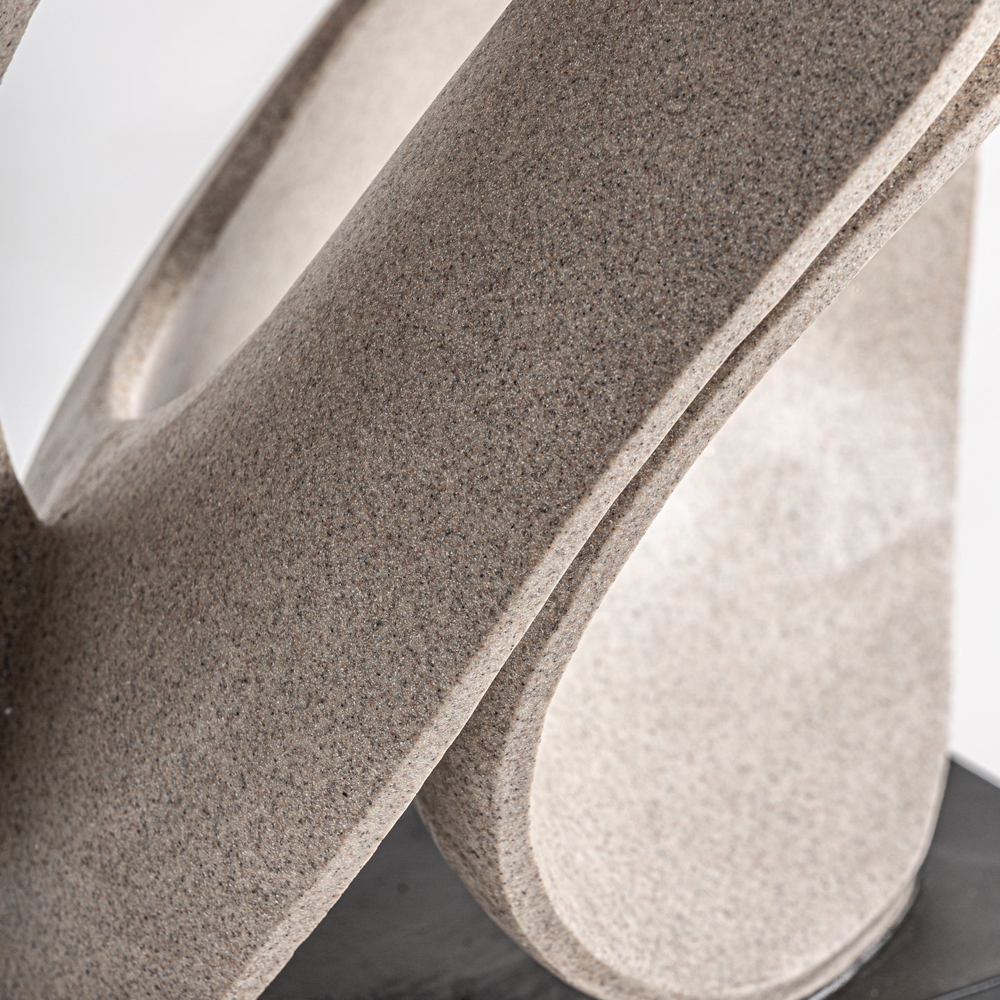 Detalle de METIS, una figura decorativa en resina beige (31×24×45 cm), con suaves bucles curvos, sobre una base negra y fondo liso, ideal para la decoración contemporánea.