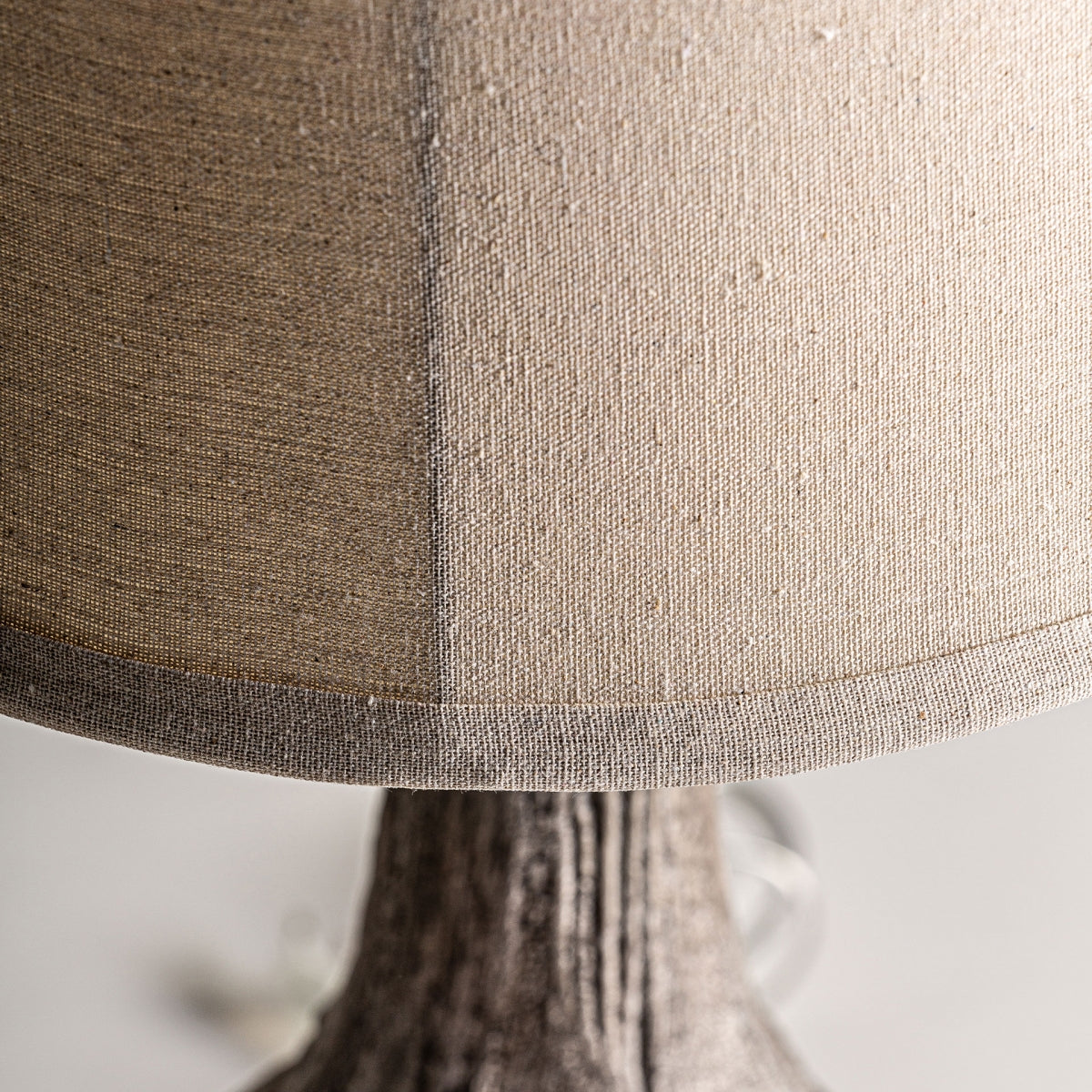 Primer plano de la Lámpara de sobremesa en resina marrón envejecido Hadra con pantalla texturizada en color beige y base símil madera, ideal para una iluminación suave y realzar una decoración de estilo rústico.