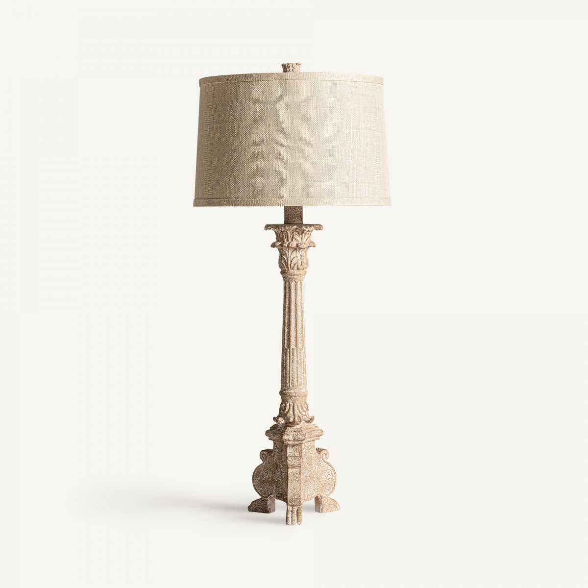 La lámpara de sobremesa en resina y algodón Amira, con base tallada y pantalla cilíndrica beige, es ideal para una iluminación elegante. Se muestra sobre fondo blanco sencillo.