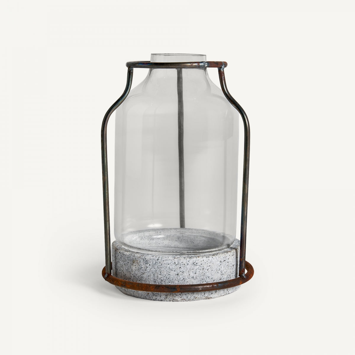 El Portavela en vidrio y piedra Lumina presenta un frasco de vidrio transparente con marco de metal y base de concreto, sobre un fondo blanco, resaltando calidez y elegancia en su diseño contemporáneo.