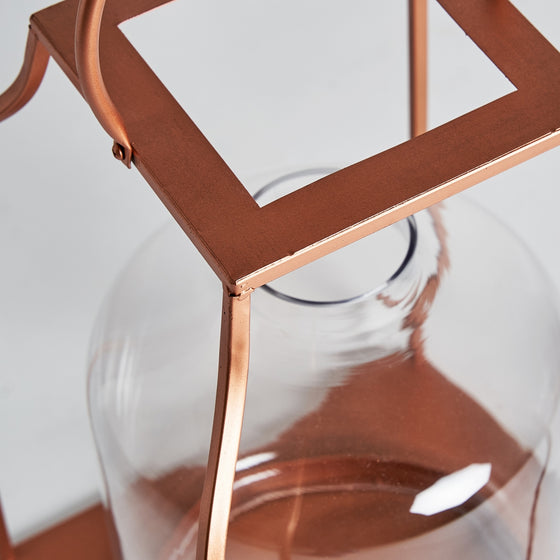 Primer plano del Farol en vidrio y acero cobre Faro con tapa cuadrada que desprende una iluminación cálida.